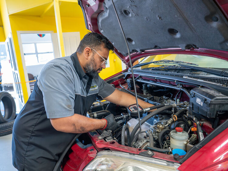 Hamilton Auto Centre mechanic servicing the engine of a red car