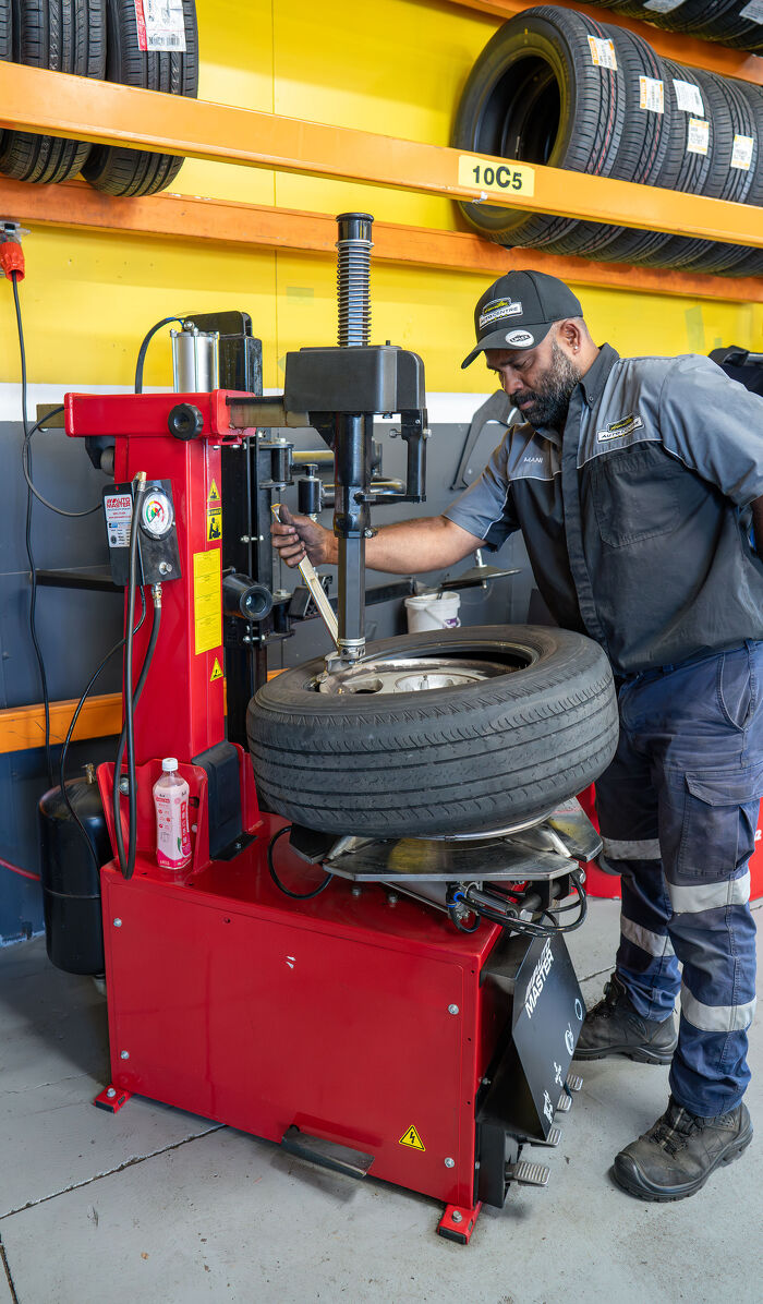 Hamilton Auto Centre technician fitting a tyre using a red tyre changer machine