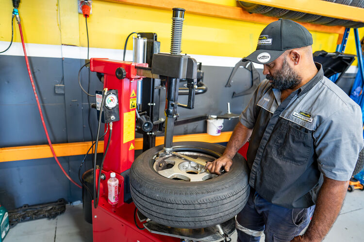 Hamilton Auto Centre technician fitting a tyre using a red tyre changer machine