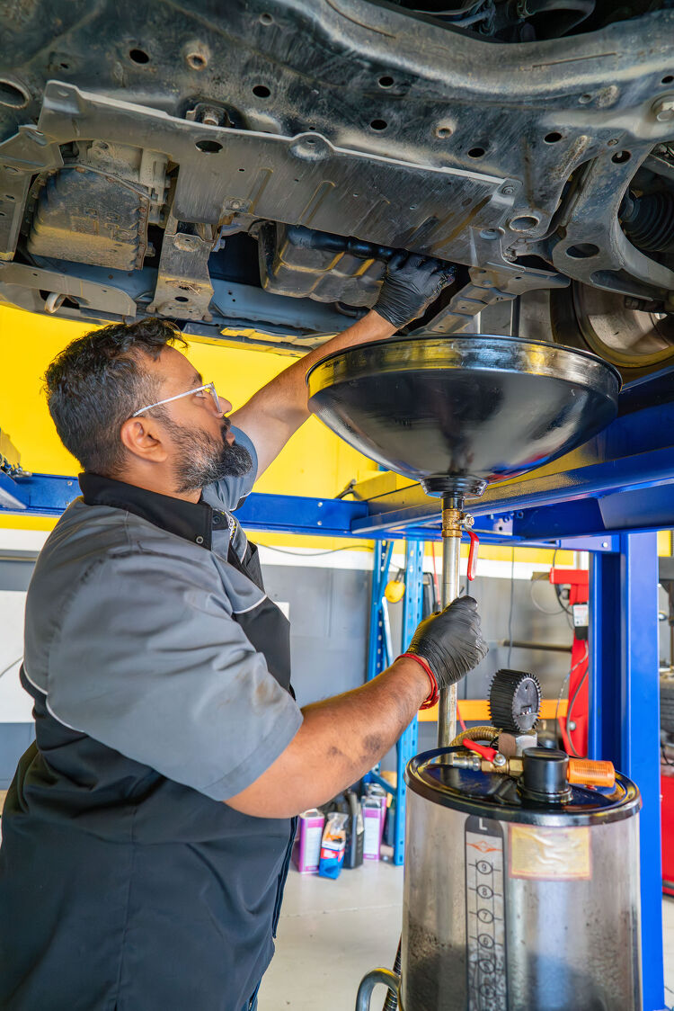 Hamilton Auto Centre mechanic performing an oil change using a waste oil drainer
