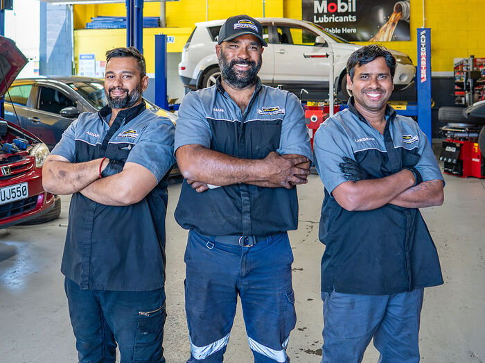 Hamilton Auto Centre mechanics smiling in the workshop with vehicles in background